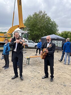 Zwei Musiker im Vordergrund mit Gitarre und Geige.