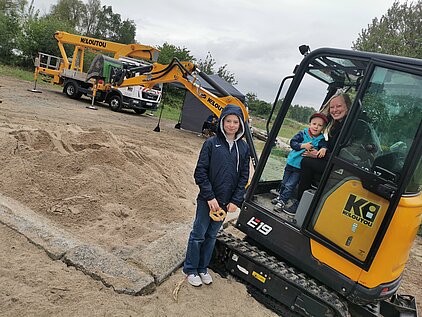 Gelber Bagger mit schwarzem Arm auf einer Baustelle mit Sand und Erde