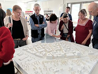 Menschen von vorne mit Blick auf das Modell vom WarnowQuartier.