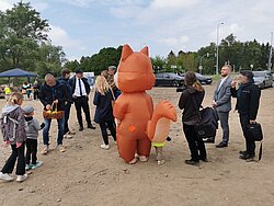 Blick auf eine Personengruppe. In der Mitte steht ein Eichhörnchen im Kostüm.