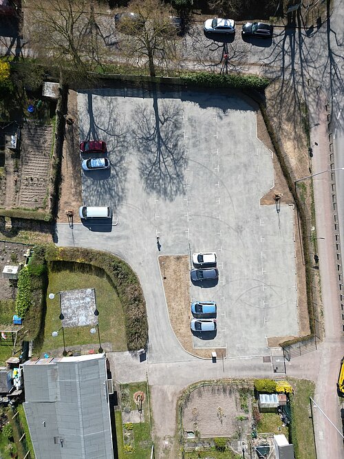 Luftaufnahme des fertiggestellten Parkplatzes der Kleingartenanlage Fährhufe in Gehlsdorf mit mehreren geparkten Autos in verschiedenen Farben und Anordnungen.