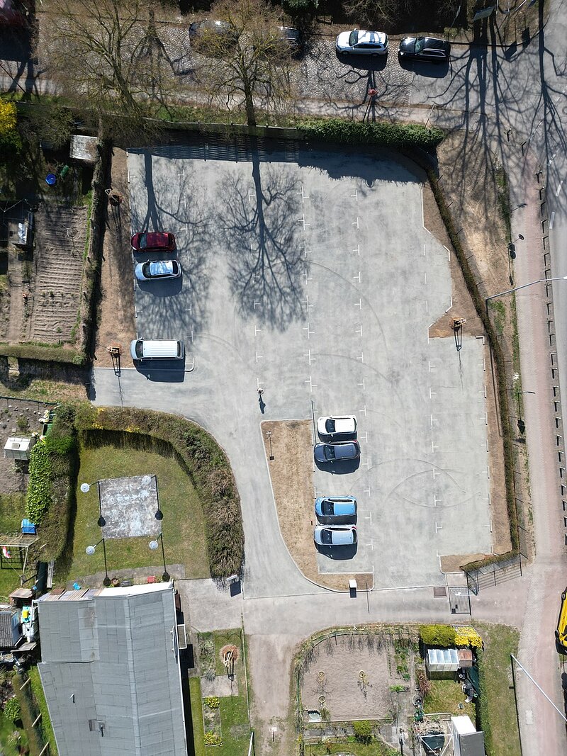 Luftaufnahme des fertiggestellten Parkplatzes der Kleingartenanlage Fährhufe in Gehlsdorf mit mehreren geparkten Autos in verschiedenen Farben und Anordnungen.