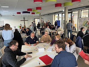 Eine Gruppe von Menschen sitzt am Tisch und schreibt.