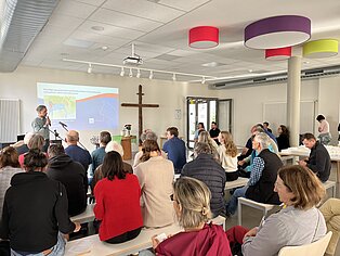 Viele Menschen von hinten sitzend in einem Raum.