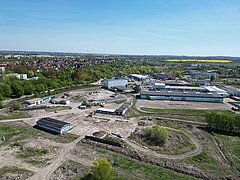 Luftaufnahme des Industrie- und Gewerbegebiets mit mehreren Gebäuden, umgeben von Grünflächen und dem Stadtteil Dierkow im Hintergrund
