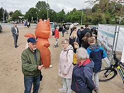 Gruppe von Menschen, die im Freien stehen und sich teilweise unterhalten.