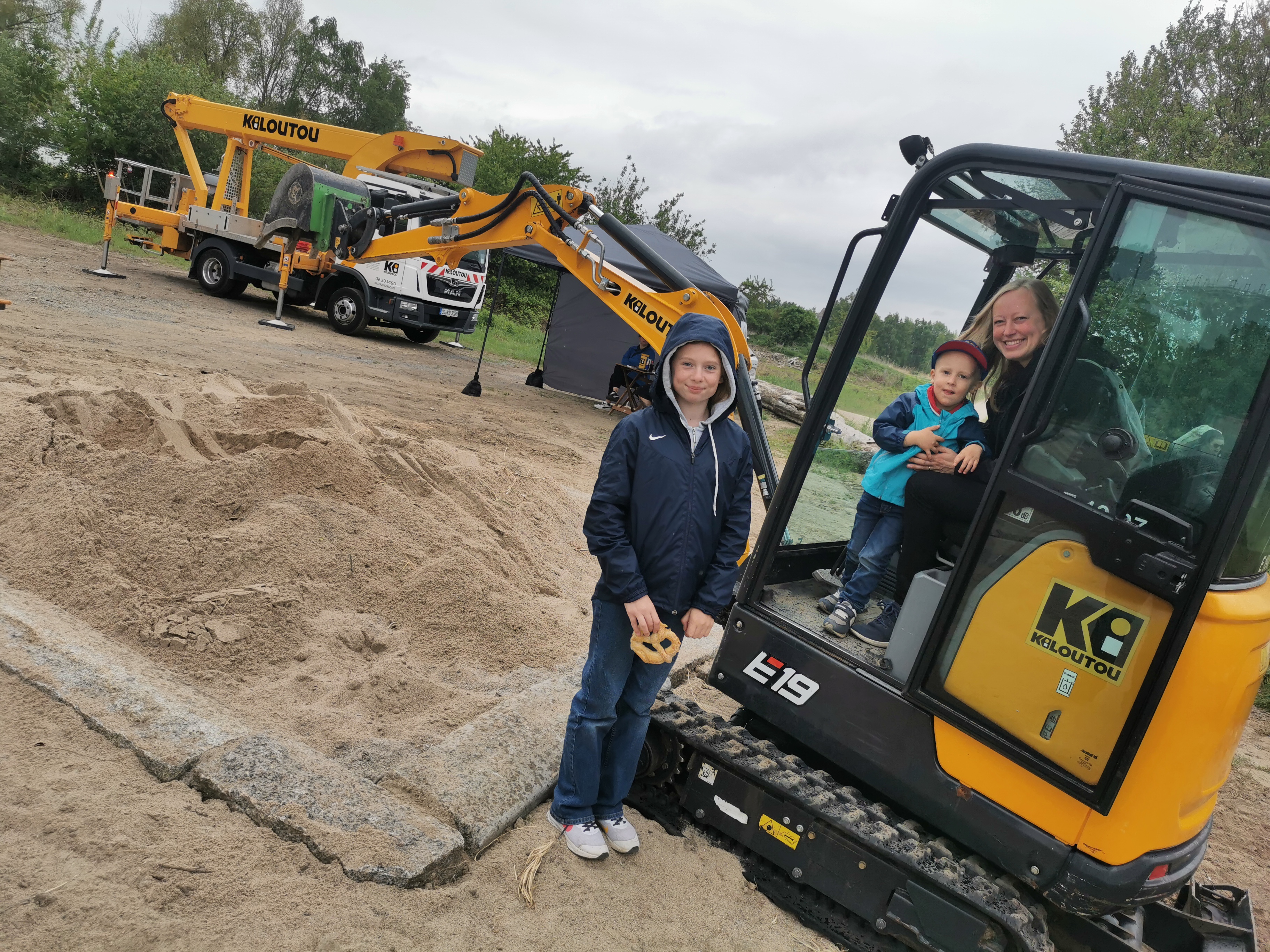 Gelber Bagger mit schwarzem Arm auf einer Baustelle mit Sand und Erde