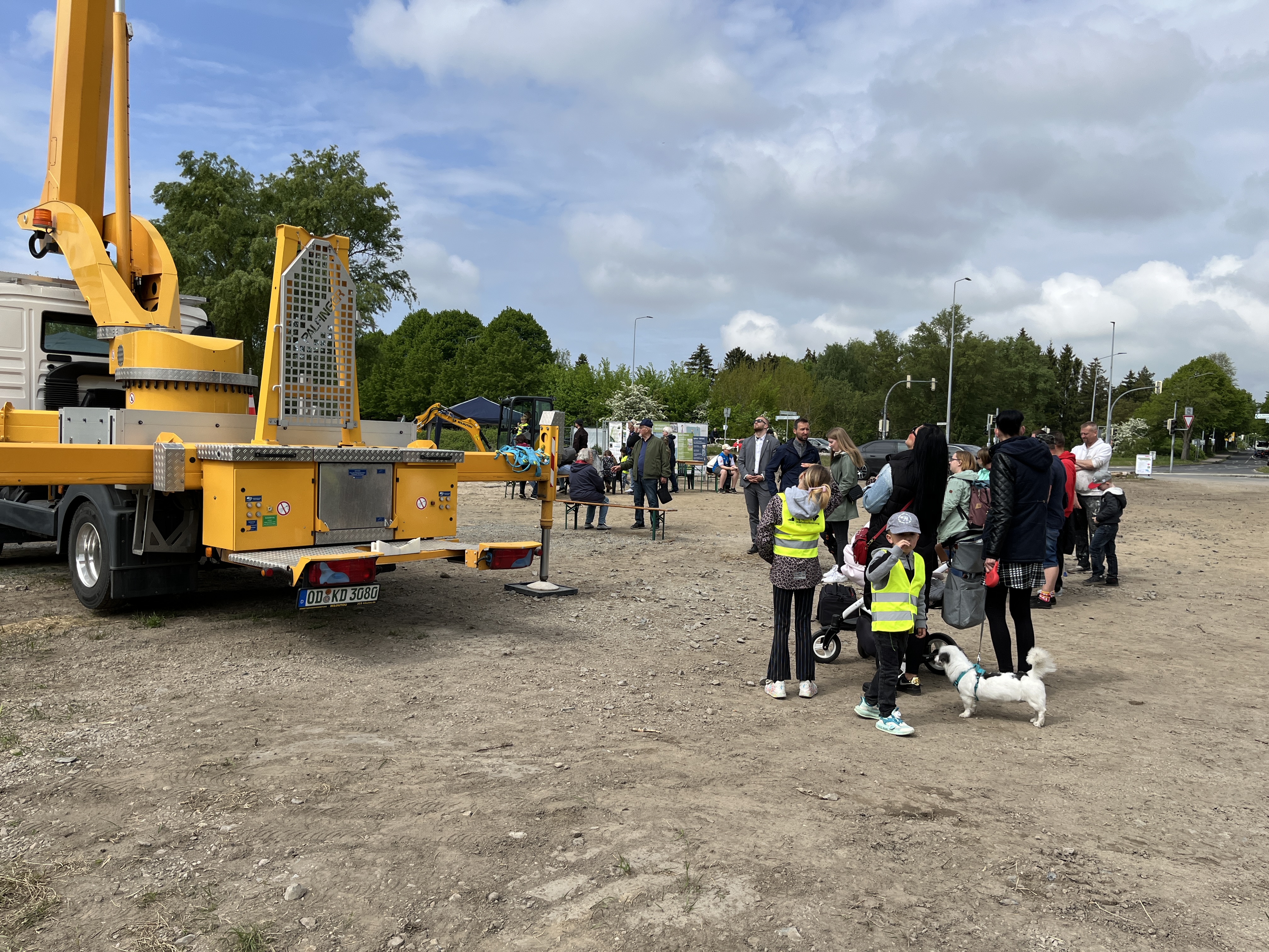 Hebebühne auf einem Sandplatz und Mneschen daneben.